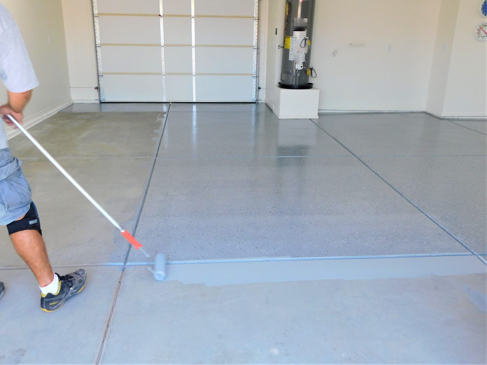 Base coat being rolled across a ground garage slab